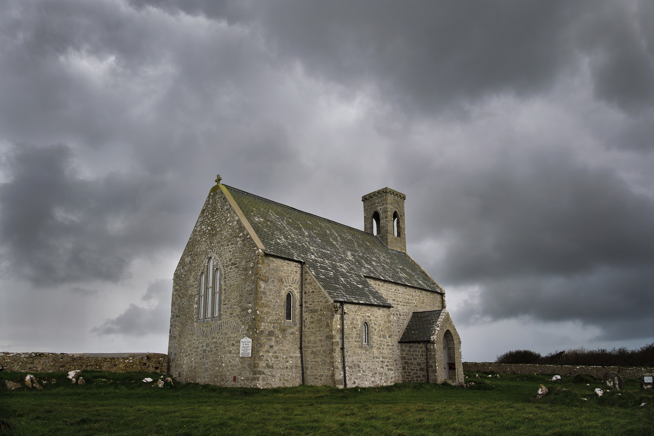 The quaint, stone building of Flimston Chapel sits under a brooding sky in Pembroke, Wales